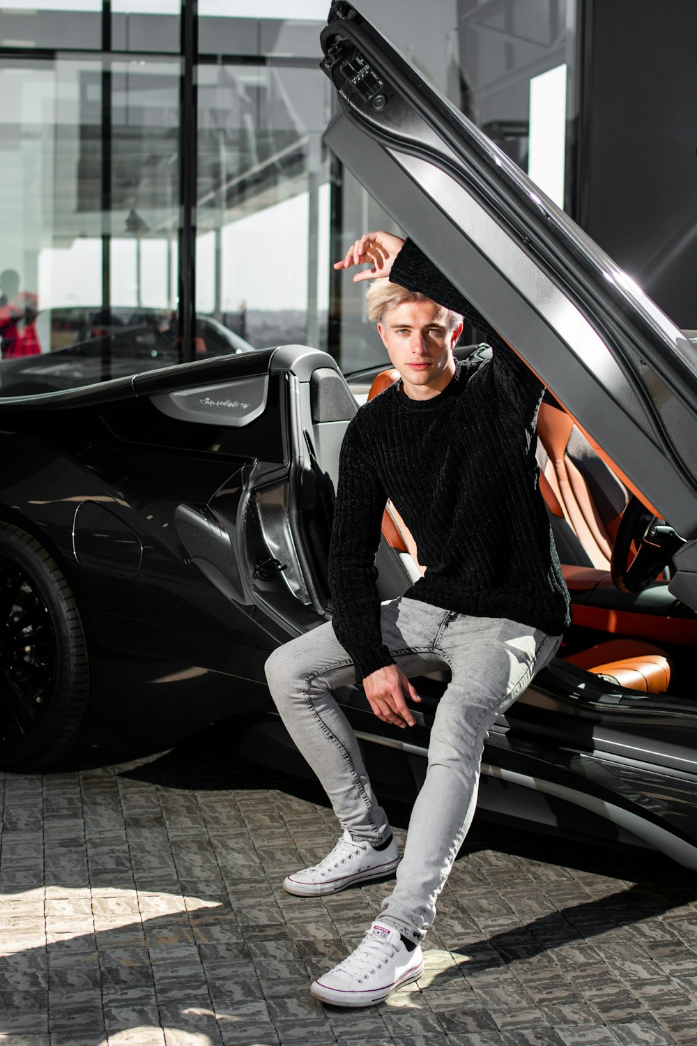 a young man sitting on the door of a car