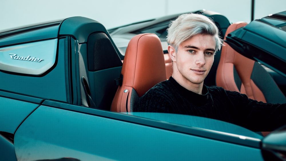 a man sitting in the back of a blue sports car