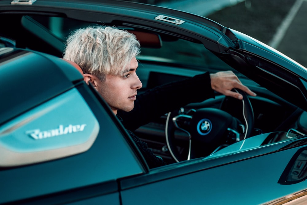 a man sitting in a blue sports car