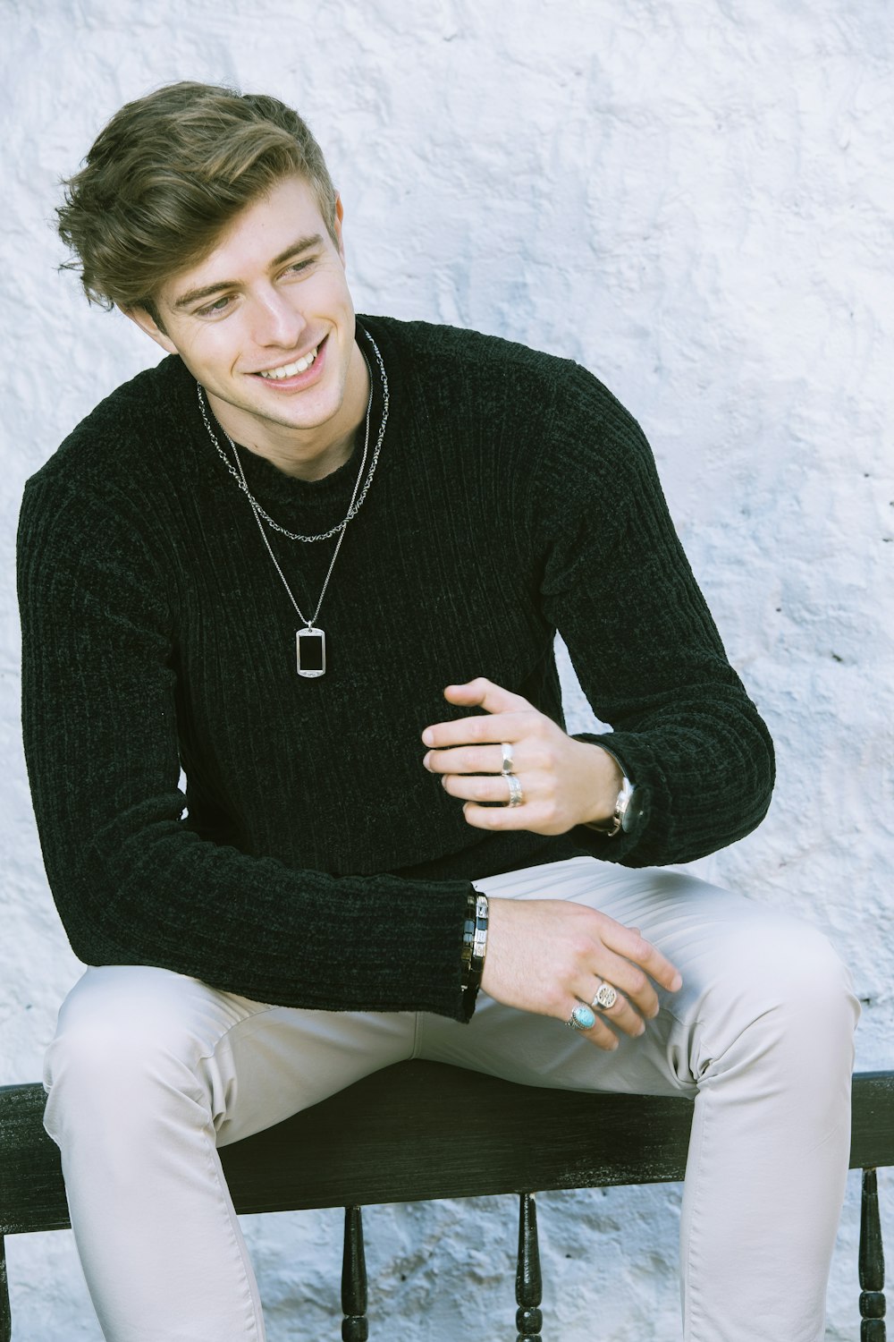 a young man sitting on a bench smiling