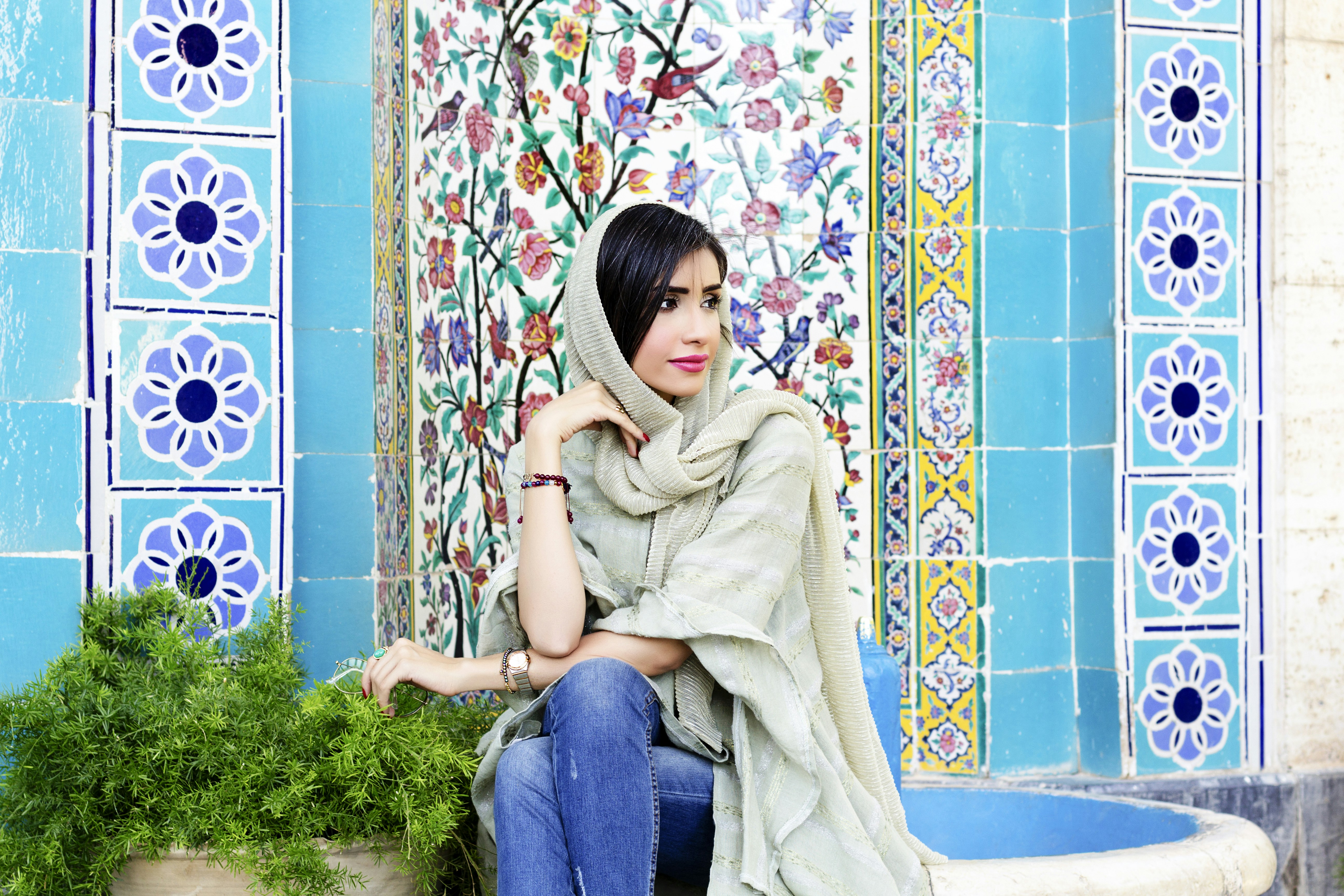 a woman sitting on a bench with a scarf over her head