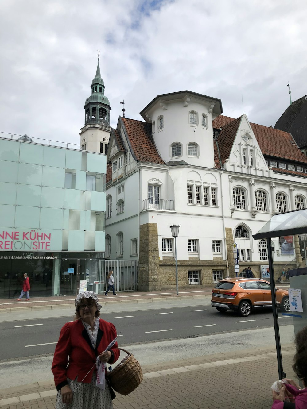 a woman walking down a street past a tall white building