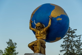 a statue of a person holding a large blue and gold globe