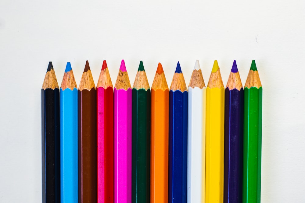 a row of colored pencils lined up against a white background