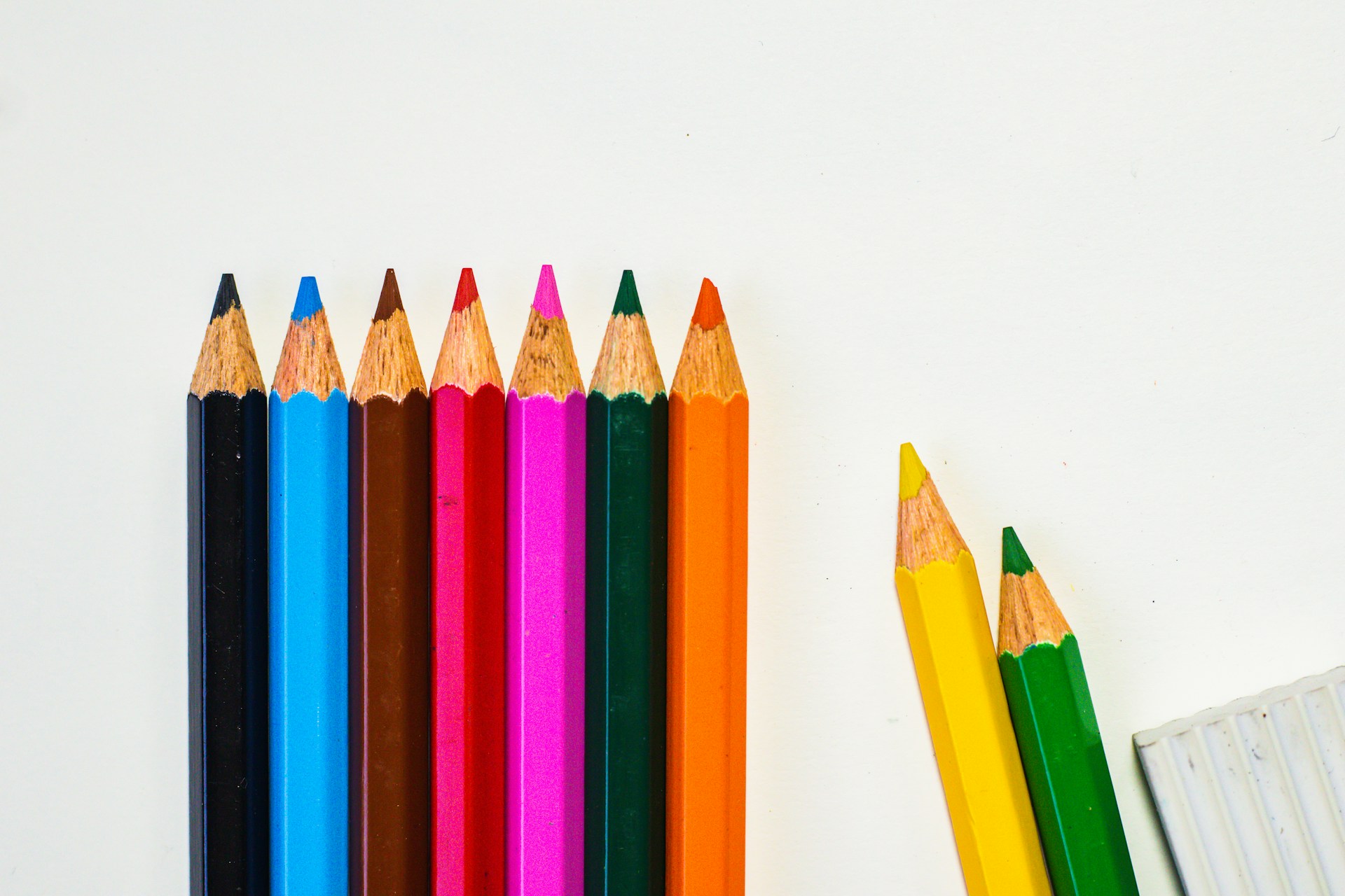 a row of colored pencils next to a pencil holder