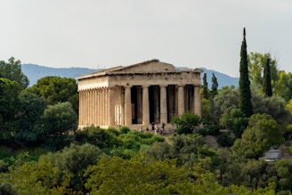 A sunlit ancient Greek temple surrounded by lush greenery and blue skies.