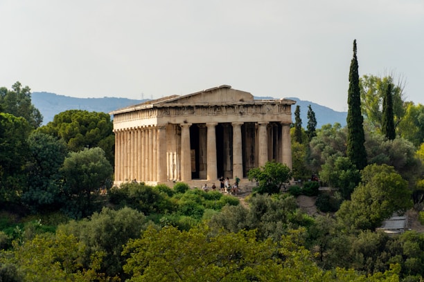 A sunlit ancient Greek temple surrounded by lush greenery and blue skies.