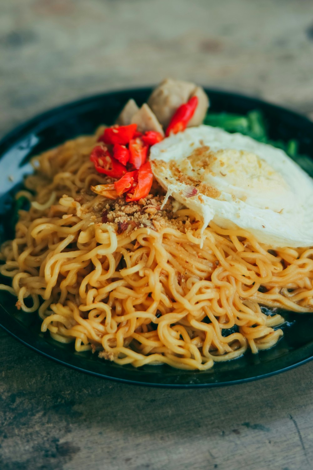 a black plate topped with noodles and meat