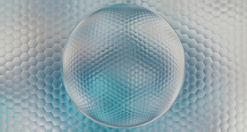 A three-dimensional sphere with a hexagonal pattern is placed against a background of similar hexagonal tiles. The perspective creates a sense of depth and texture, enhanced by the subtle use of light and shadows.
