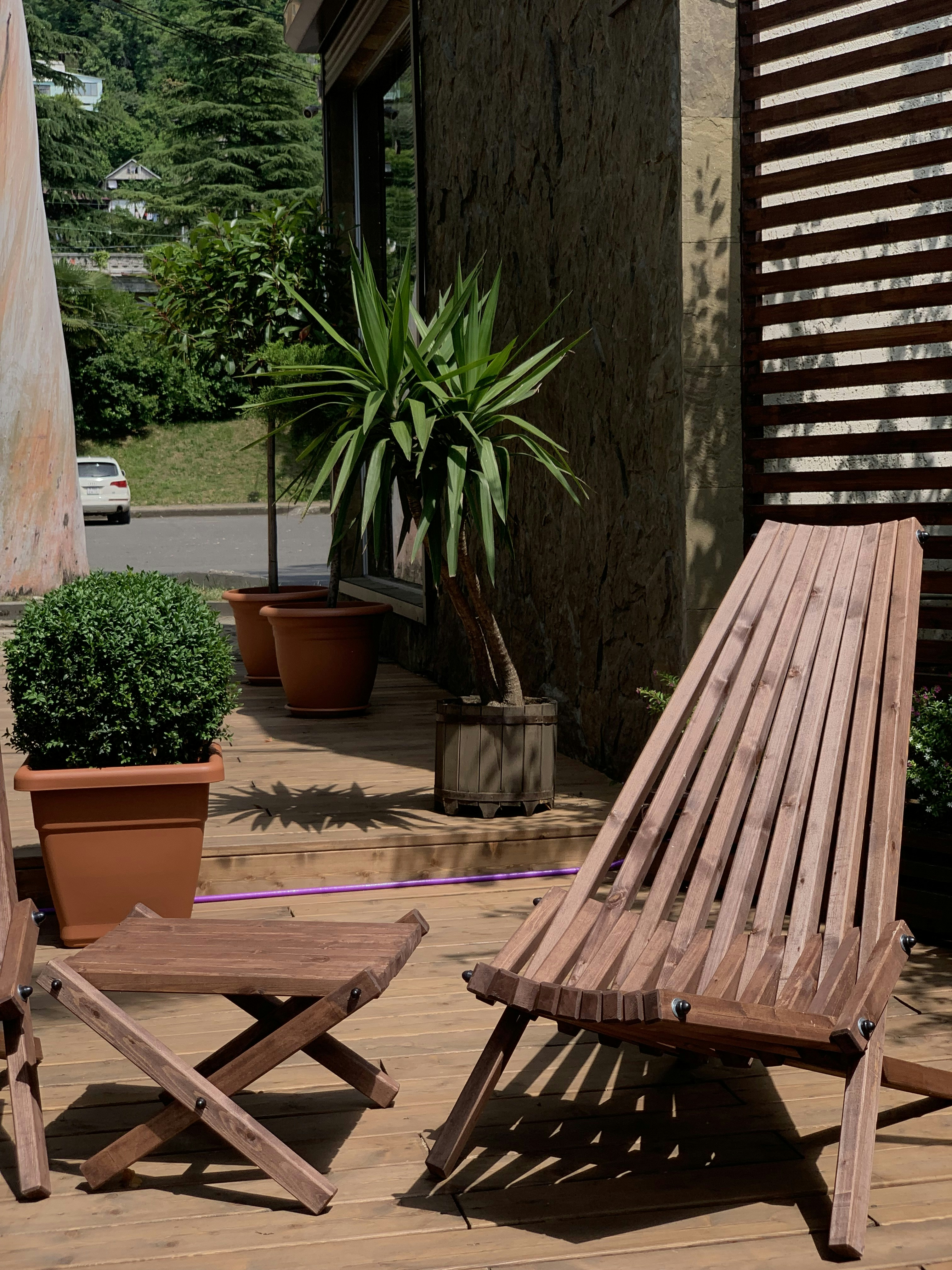 Outdoor deck staging with teak furniture, lanterns, and lush potted plants