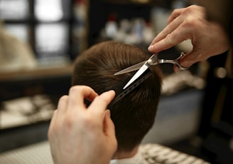 a person cutting another persons hair with a pair of scissors