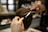 A hairdresser carefully trims a person's short, brown hair using scissors and a comb. The focus is on the precise cutting technique as the hands hold the tools expertly.