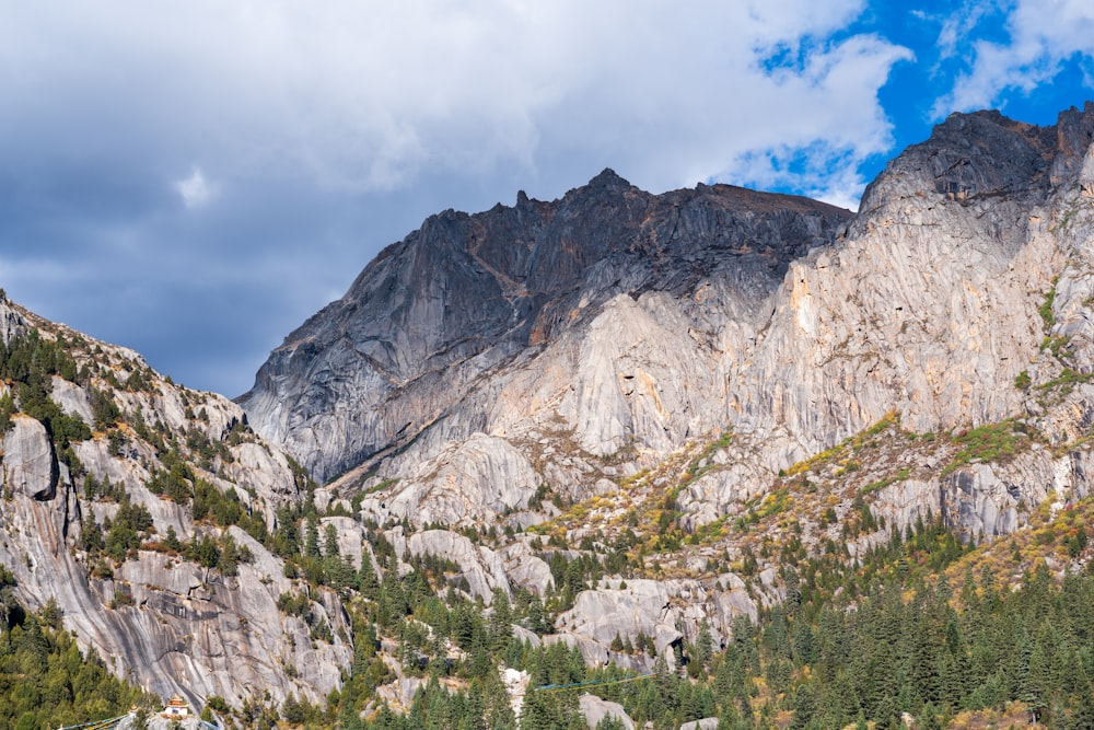 a mountain range with trees and clouds in the background