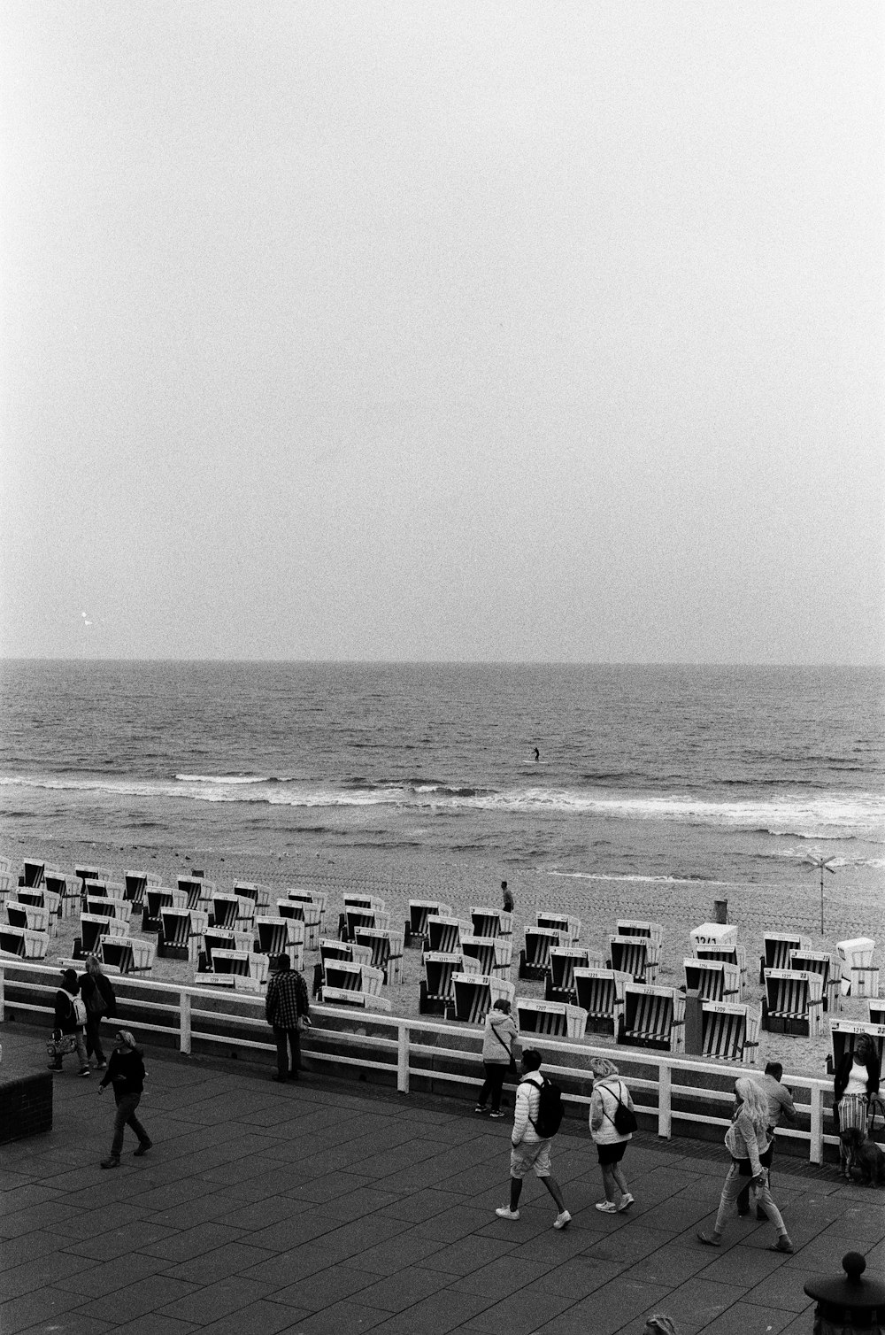 a group of people walking along a pier next to the ocean