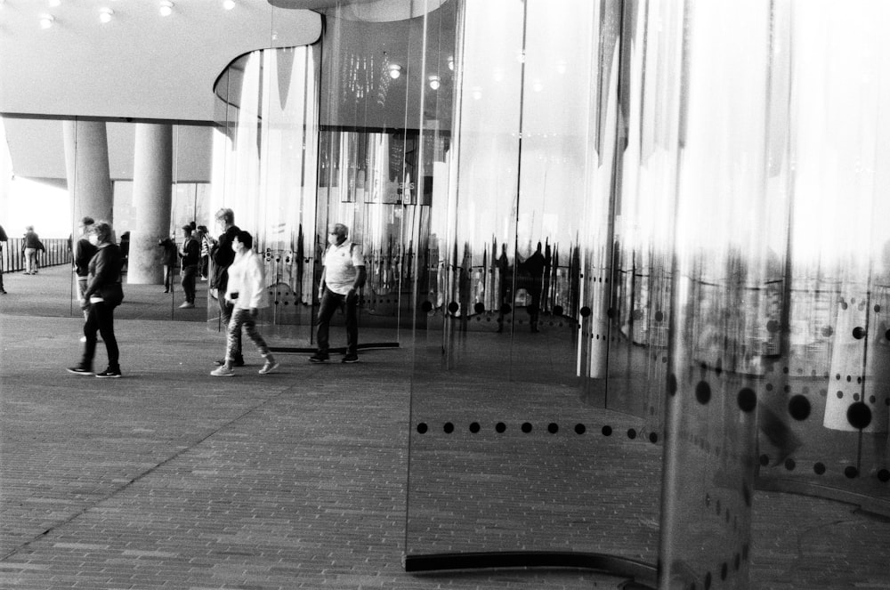 a group of people walking down a sidewalk next to a tall building