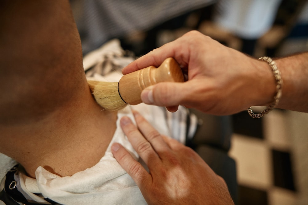 a man is shaving another mans neck with a brush