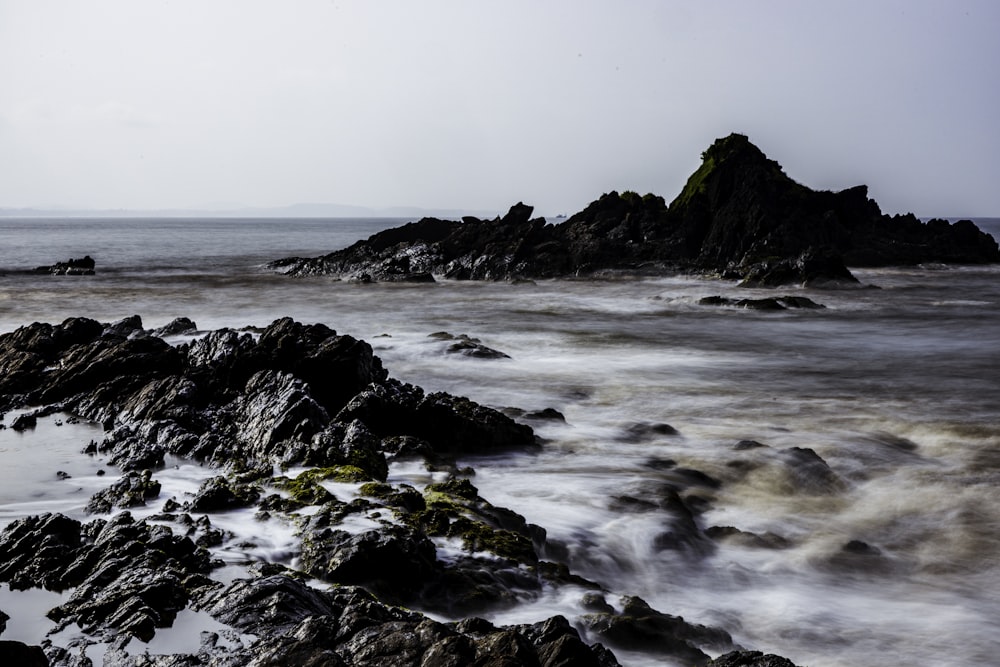 a rocky beach with a rock outcropping in the water