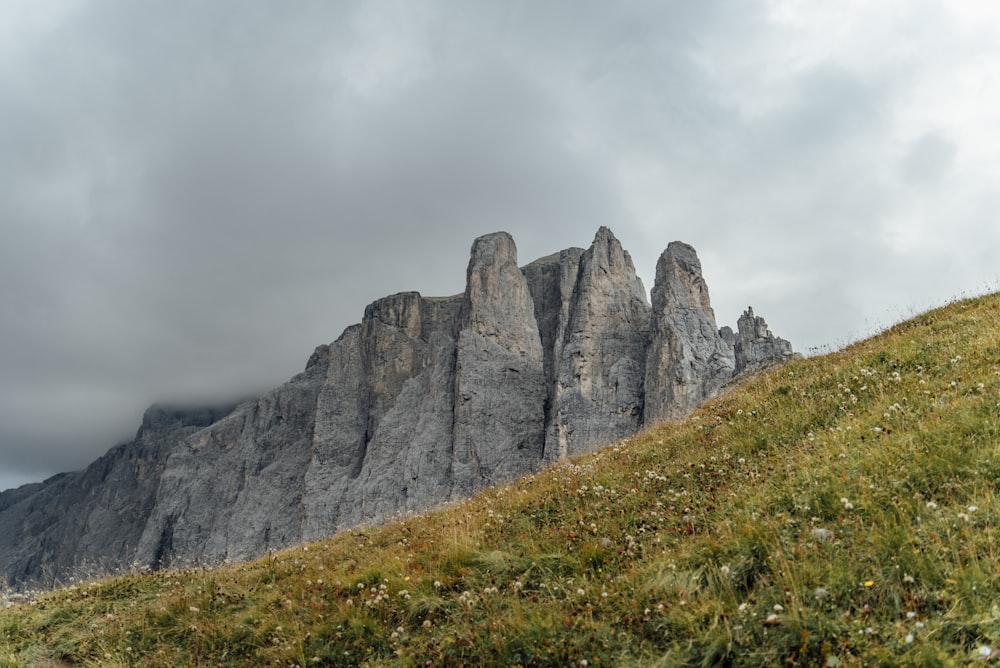 a group of tall rocks sitting on top of a lush green hillside