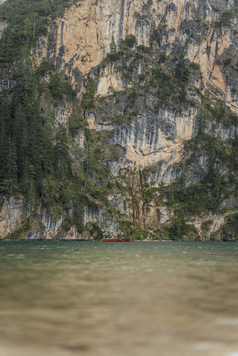 a boat floating on top of a lake next to a mountain