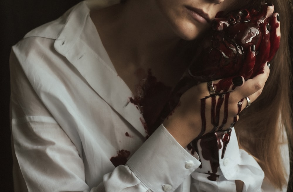 a woman in a white shirt holding a chocolate covered doughnut