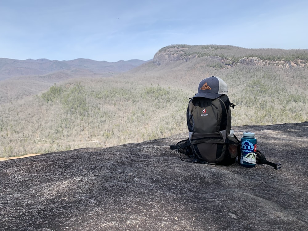 a backpack sitting on top of a rock next to a can of soda