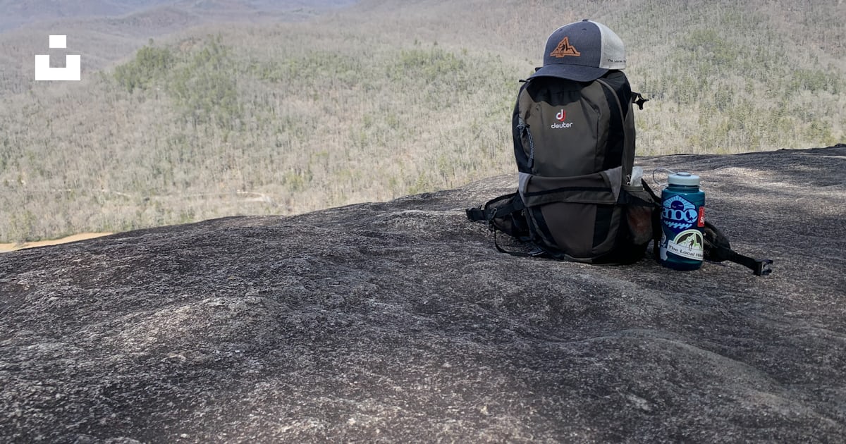 A backpack sitting on top of a rock next to a can of soda photo – Free ...