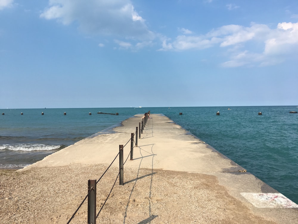 a man walking along a pier next to the ocean