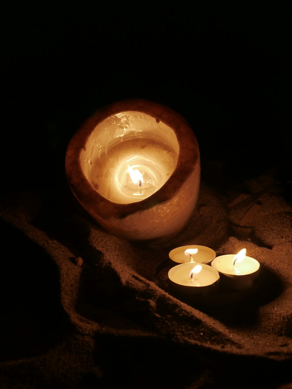 three lit candles sitting in a bowl on a table