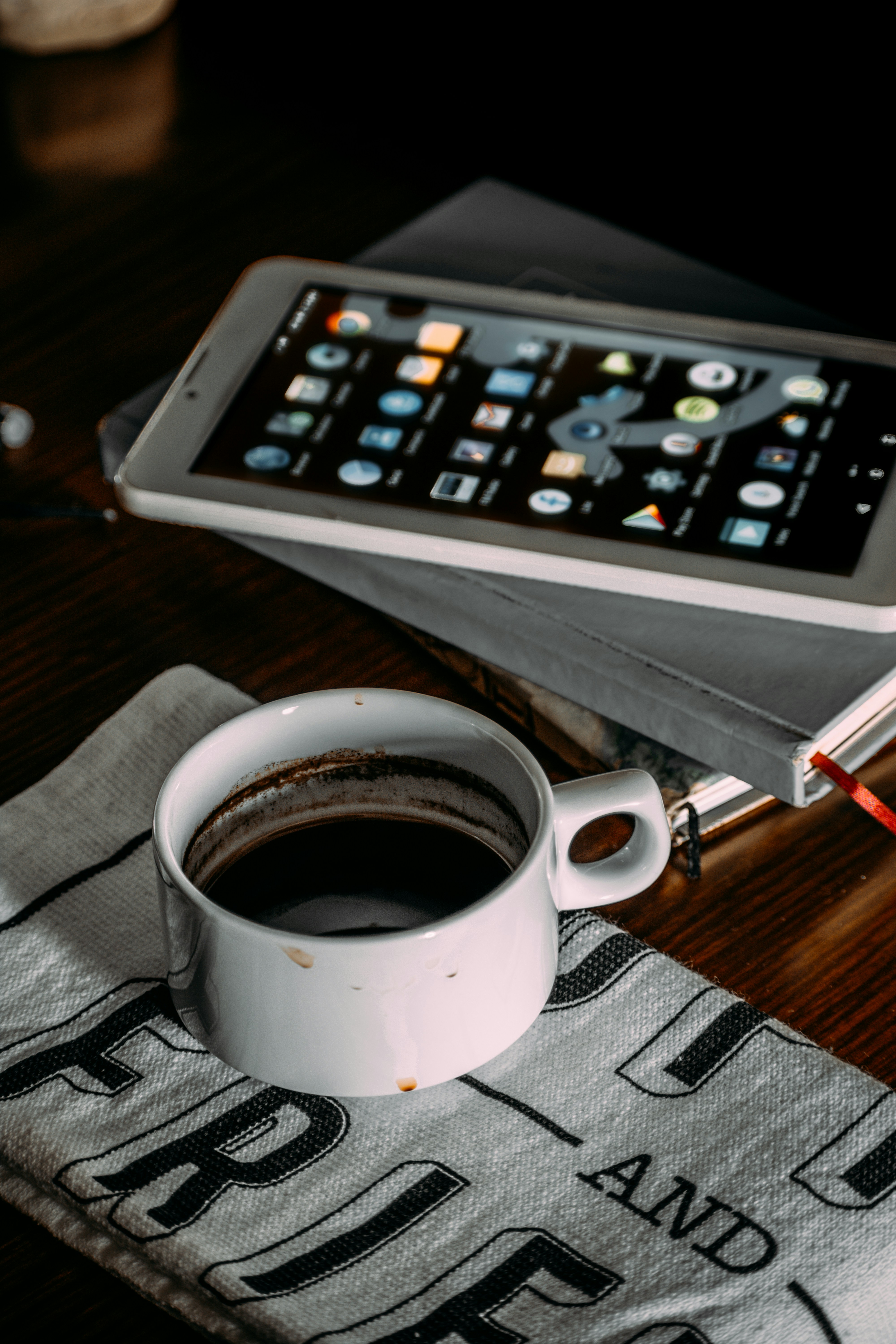 secangkir kopi dan tablet di atas meja