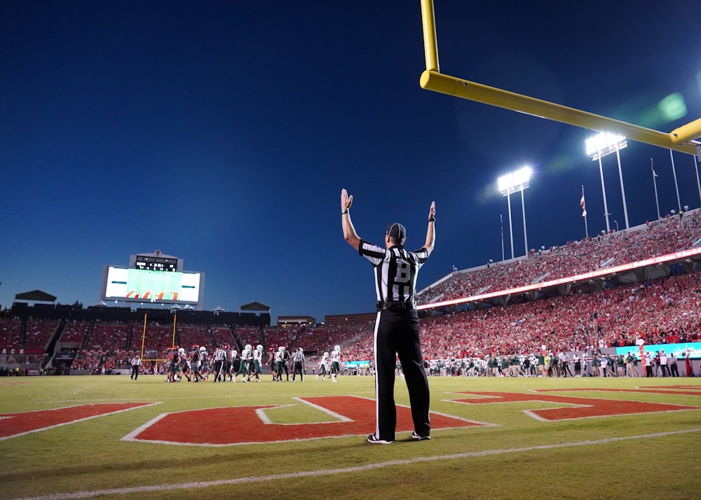 a football player standing on a field with his arms in the air