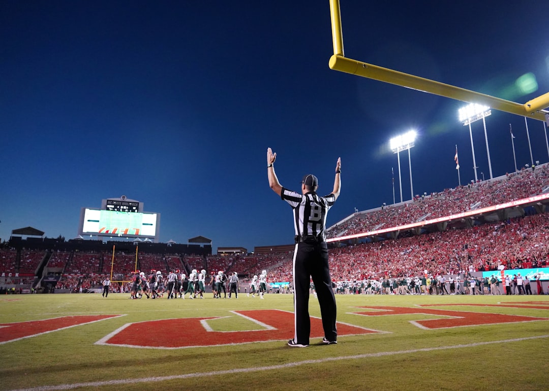 a football player standing on a field with his arms in the air,