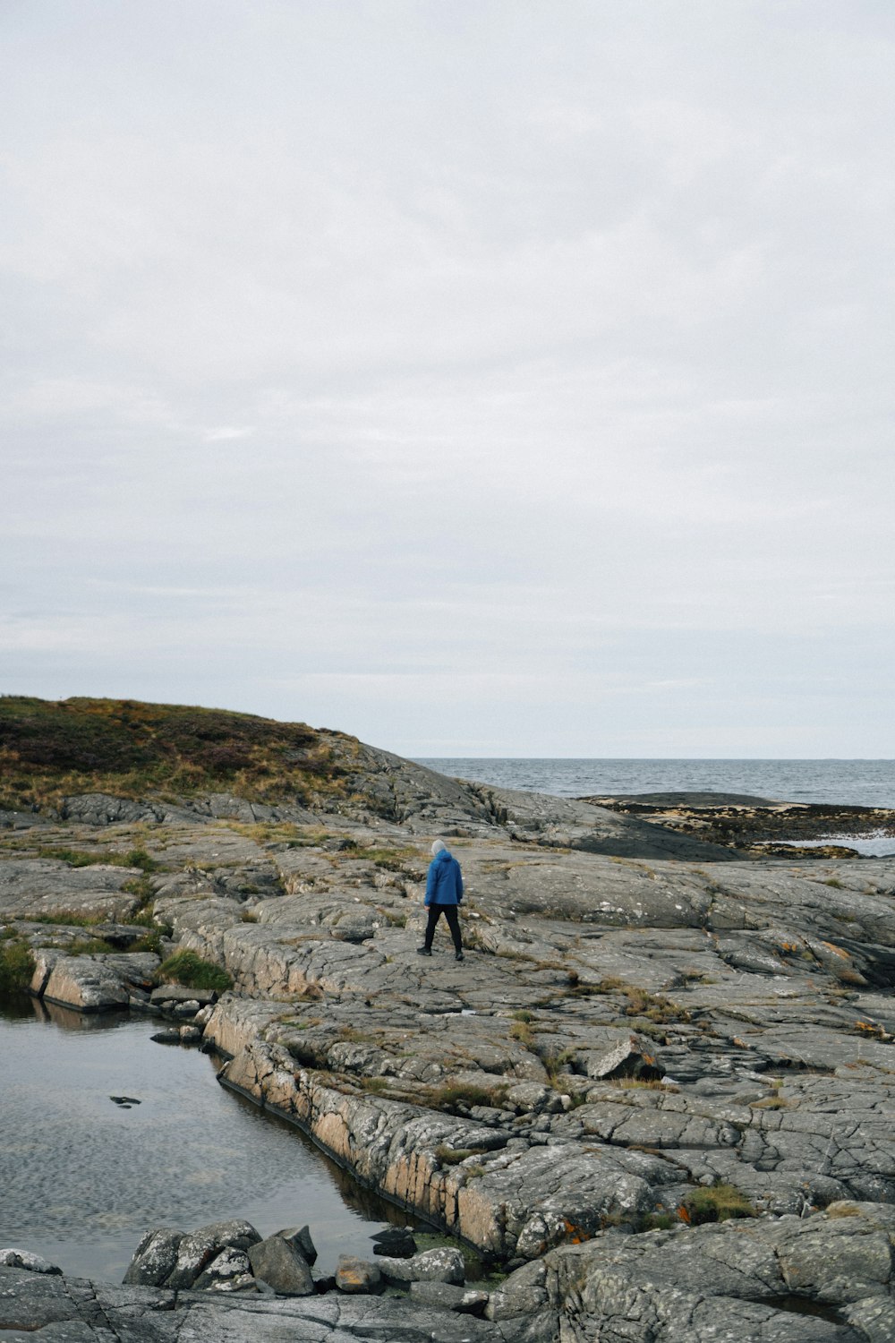 a man standing on top of a rocky beach next to the ocean