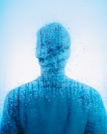 a man standing in front of a window covered in water
