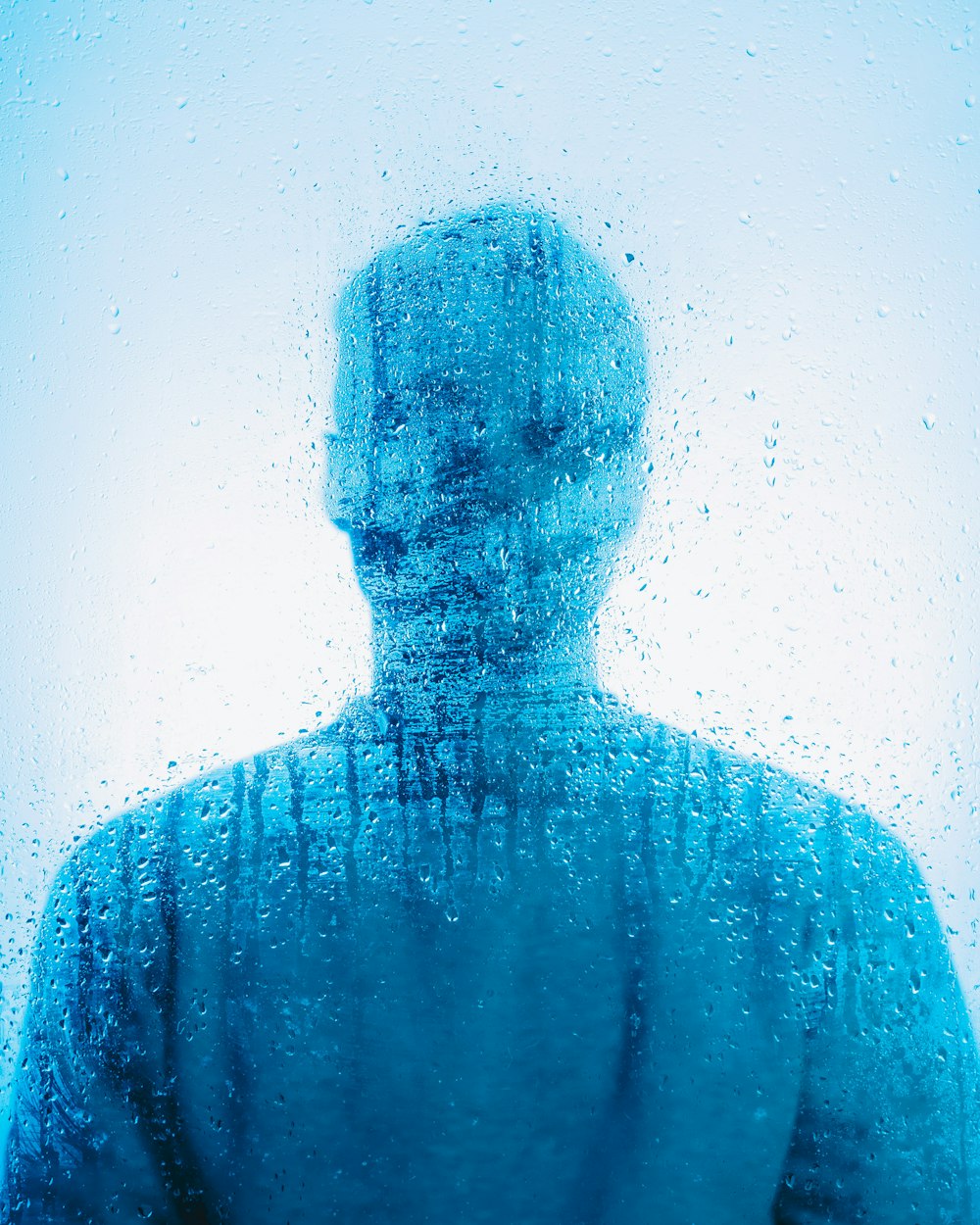 a man standing in front of a window covered in water