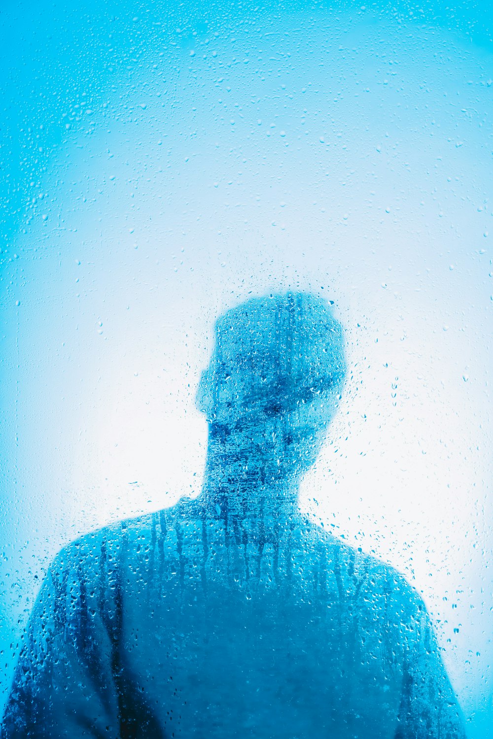 a man standing in front of a window covered in water