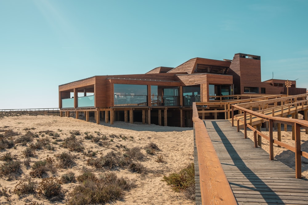 a wooden walkway leading to a building on the beach