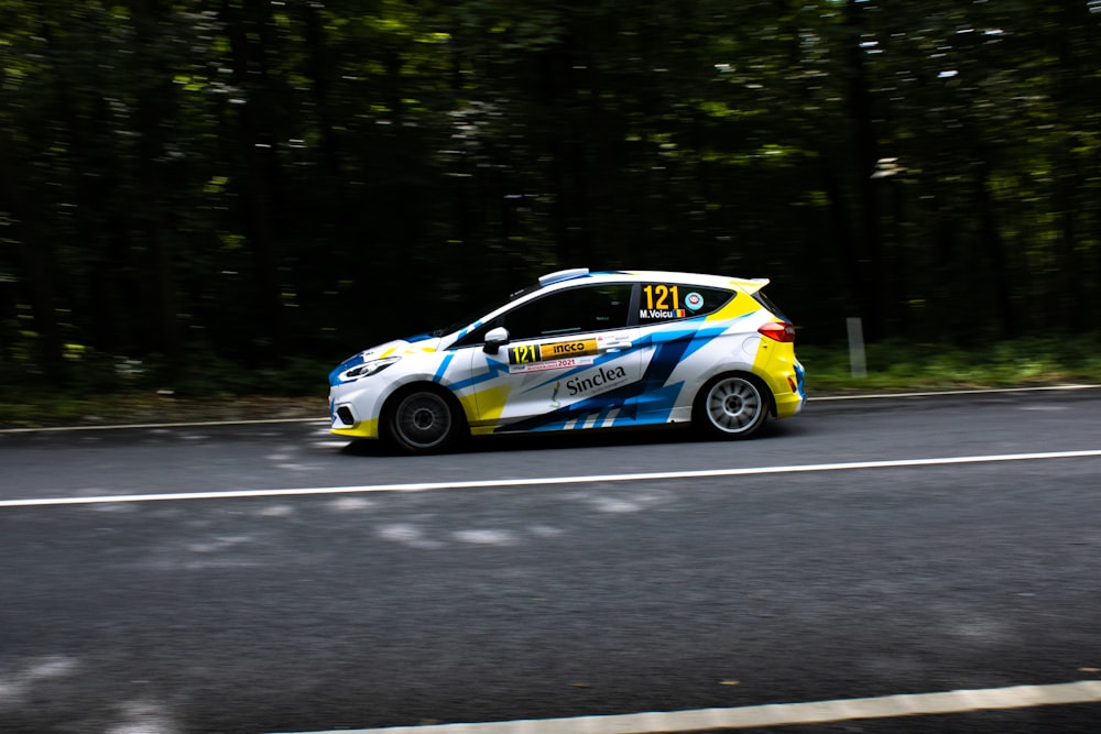 a yellow and blue car driving down a road