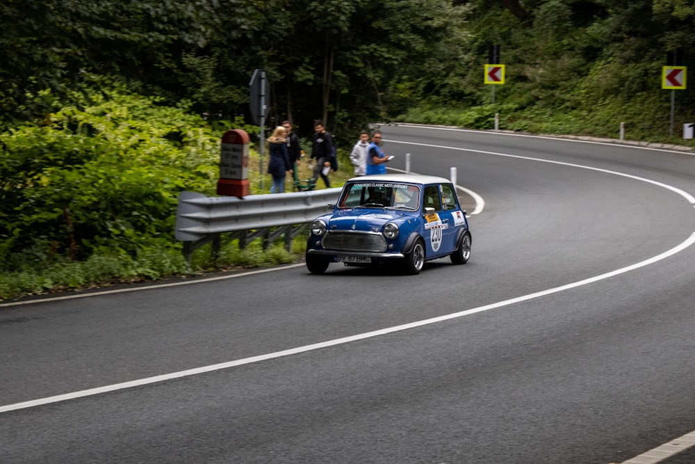 a small blue car driving down a curvy road