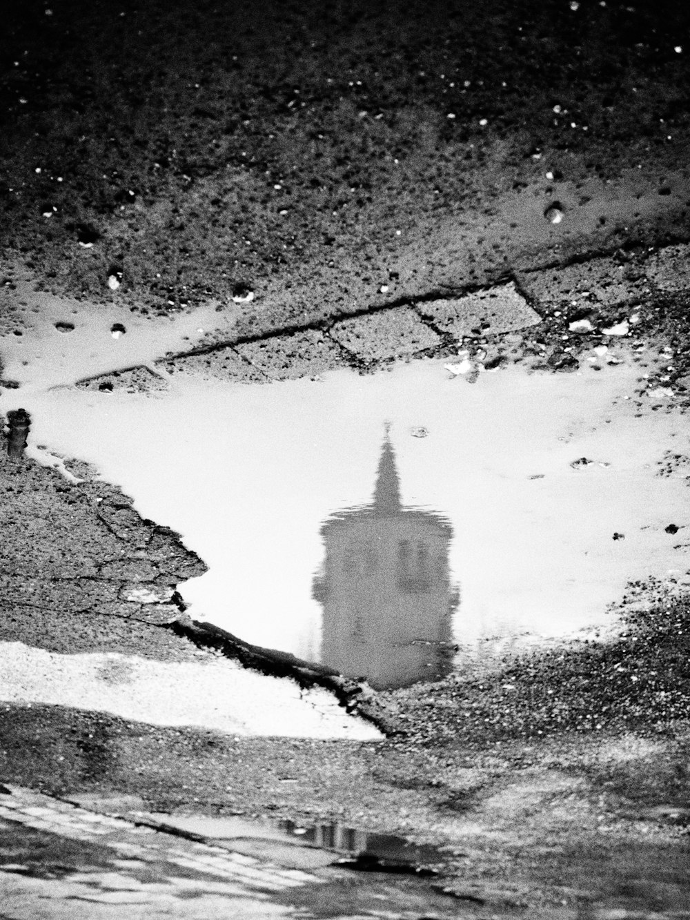 a reflection of a clock tower in a puddle of water