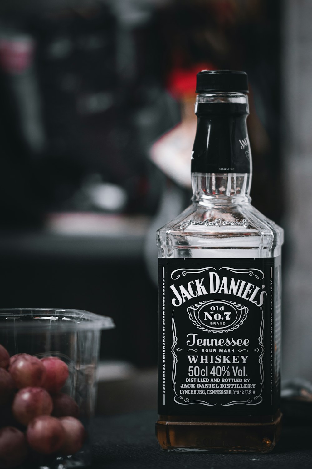 Una botella de whisky Jack Daniels junto a unas uvas