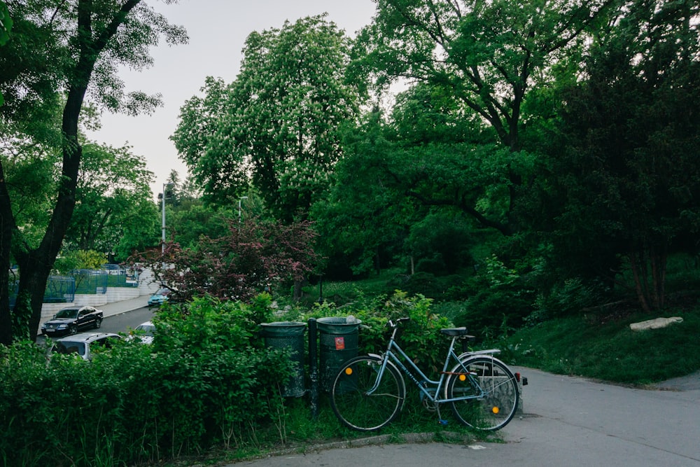 una bicicletta parcheggiata accanto a un bidone della spazzatura sul ciglio di una strada