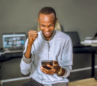 a young man holding a smart phone in his right hand