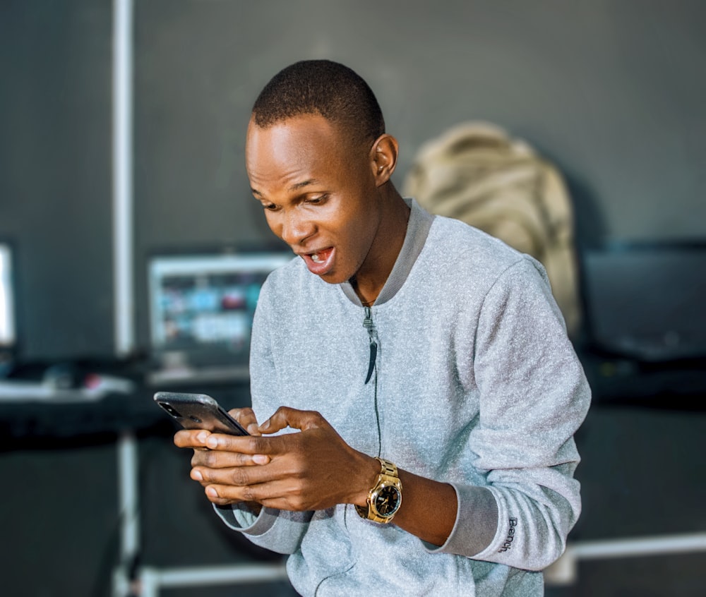 um homem olhando para o celular e rindo