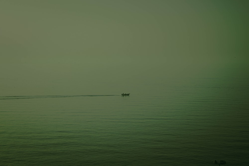 a lone boat in the middle of the ocean on a foggy day