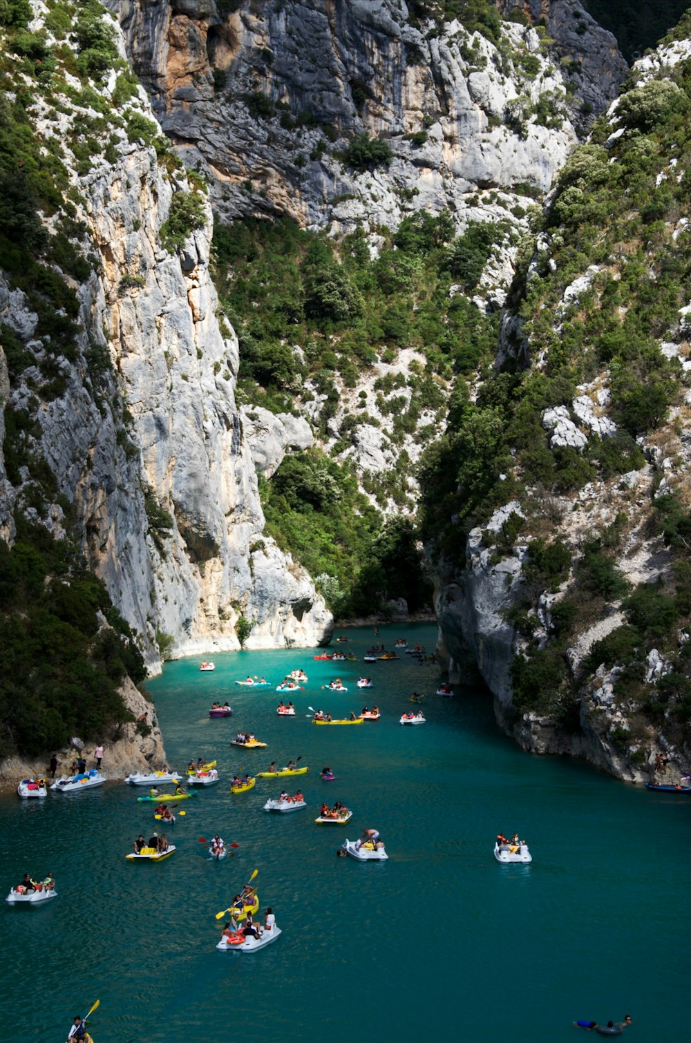 a group of boats floating down a river surrounded by mountains