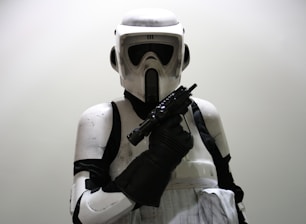 A person wearing a detailed, futuristic white and black armored suit with a helmet, holding a weapon in a defensive or ready stance.