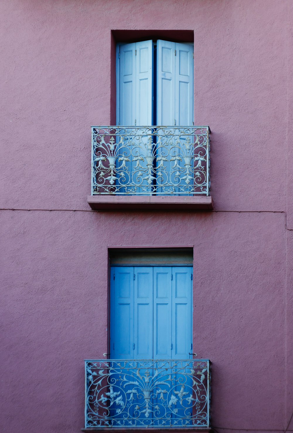 a pink building with two balconies and a blue door