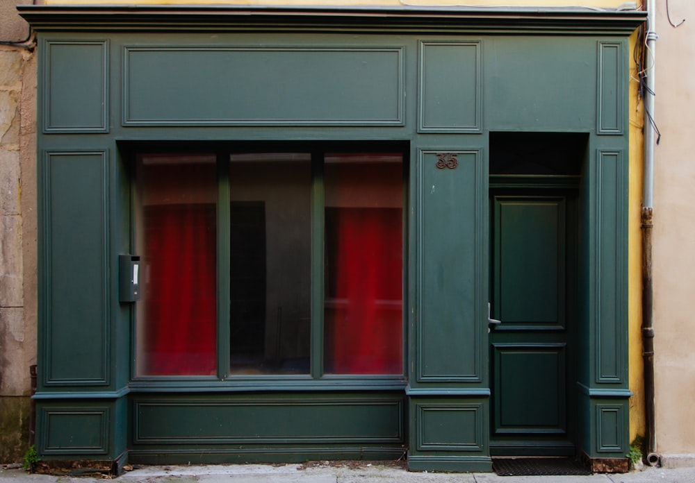 a green building with red curtains on the windows