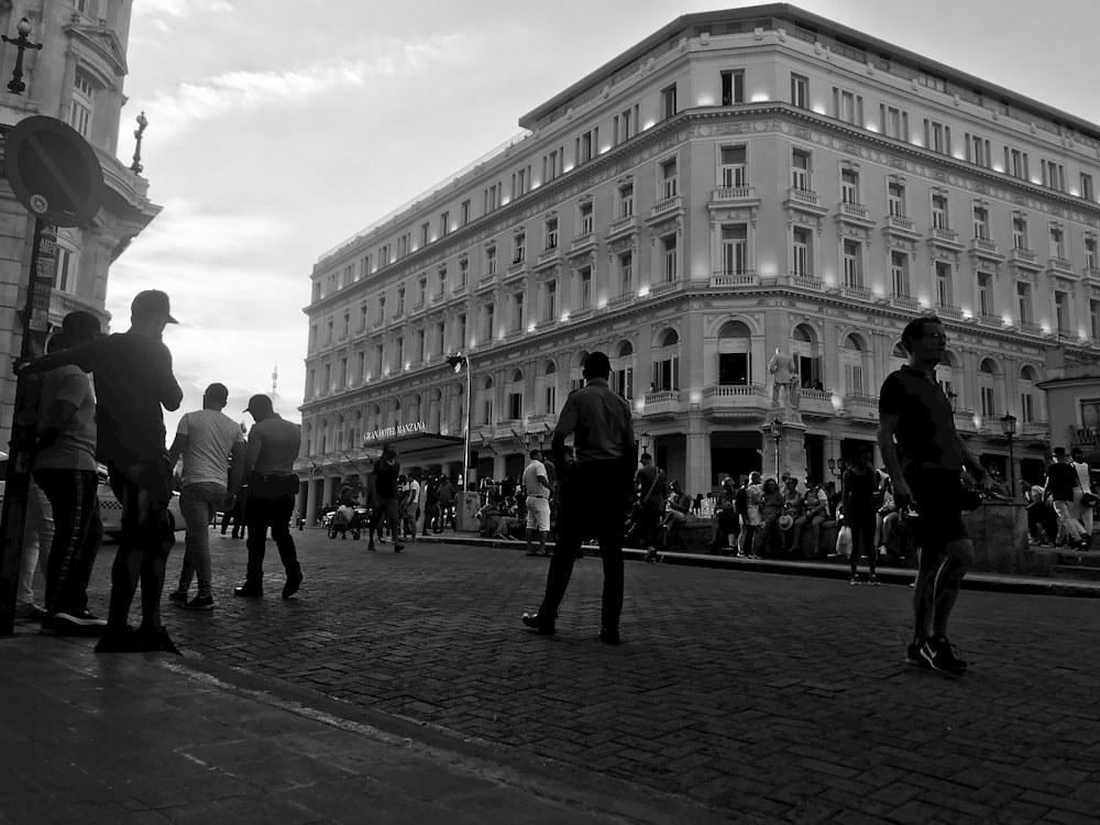 a group of people standing on a street next to a tall building