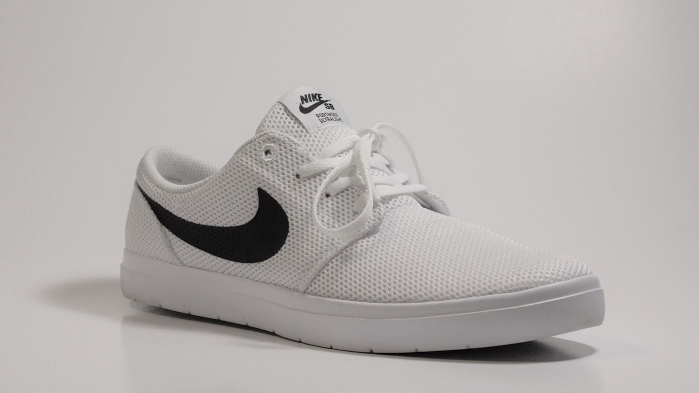 White Nike SB Stefan Janoski sneaker with a black swoosh on a plain background
